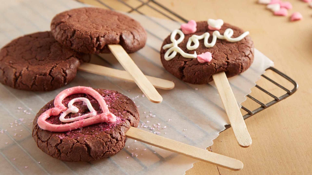 cookies on a stick decorated with pink icing