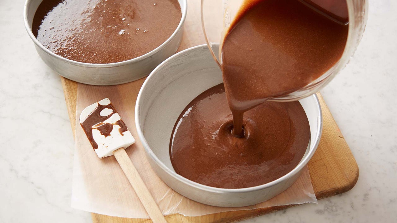 chocolate cake batter being poured into cake pans