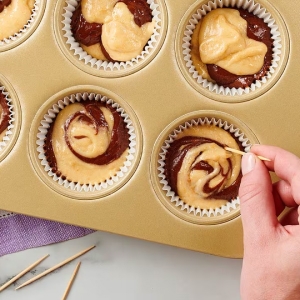 cupcake dough in baking pan being swirled with toothpick