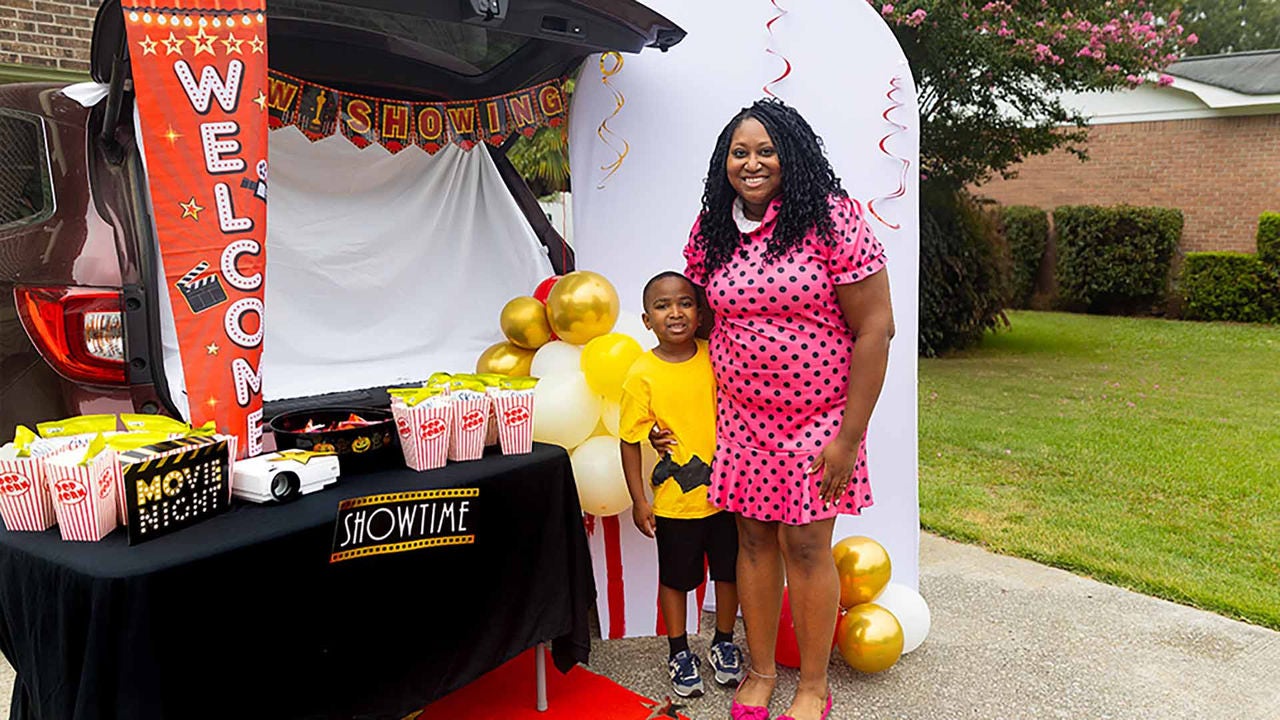 family standing in front of suv decorated to look like a drive in movie theater