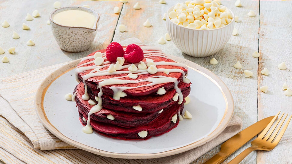 stack of red velvet pancakes topped with hersheys cream cheese baking chips