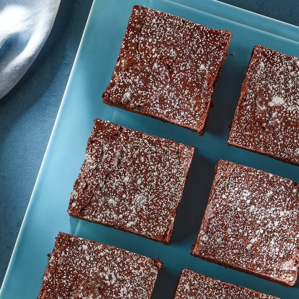 tray of ultimate vegan brownies topped with powered sugar