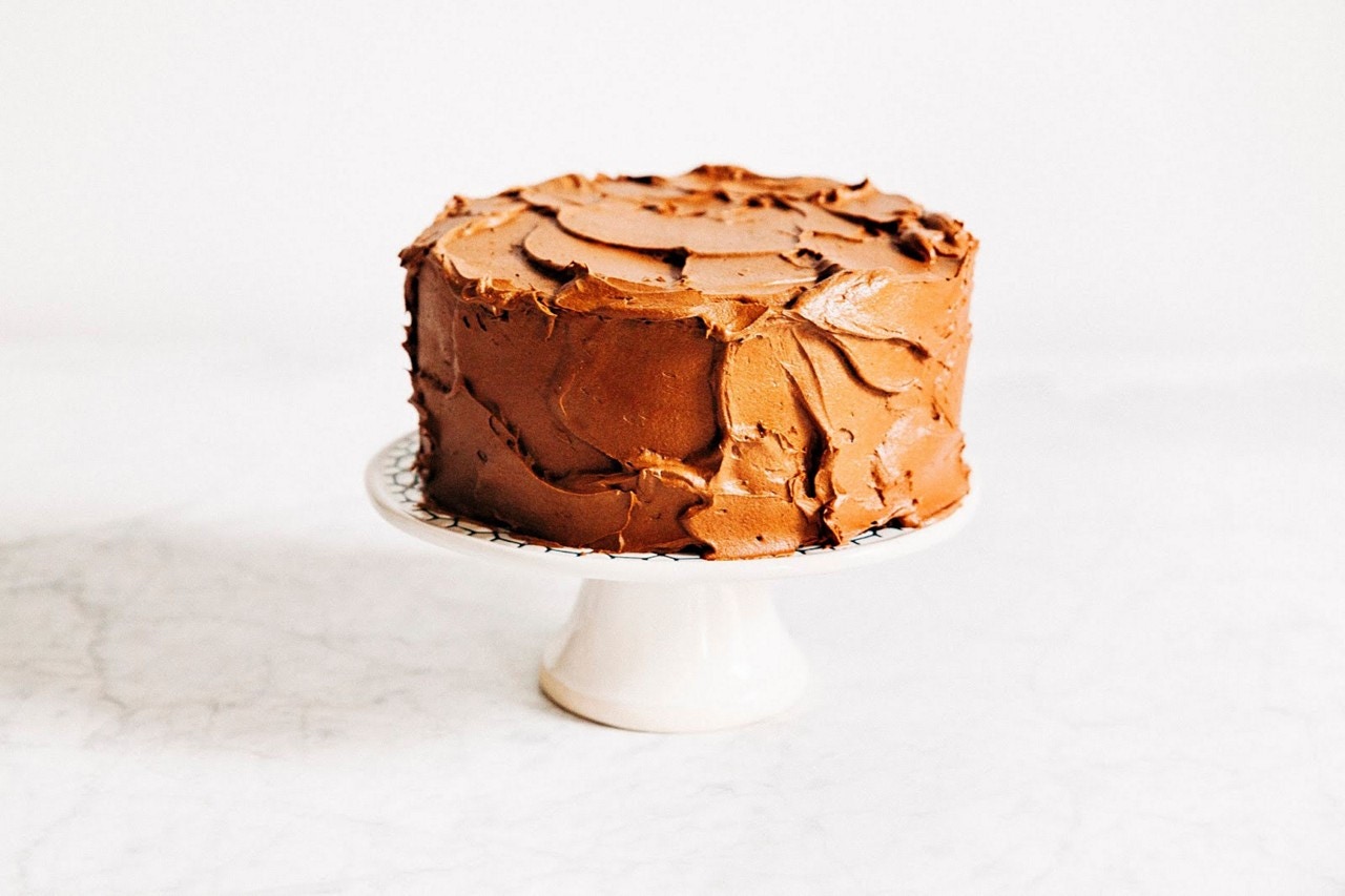 decorated cake with icing sitting on pedestal