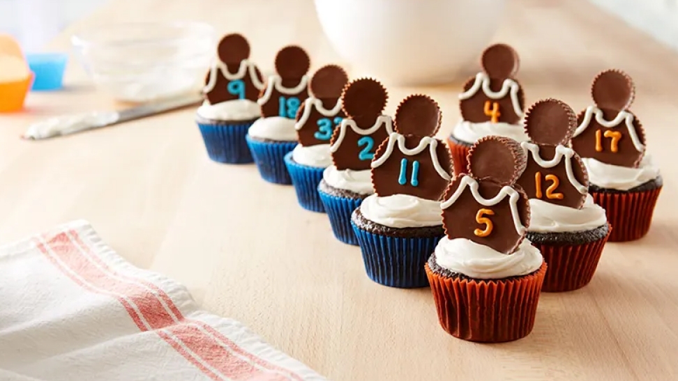 fresh batch of basketball themed cupcakes topped with reeses peanut butter cups