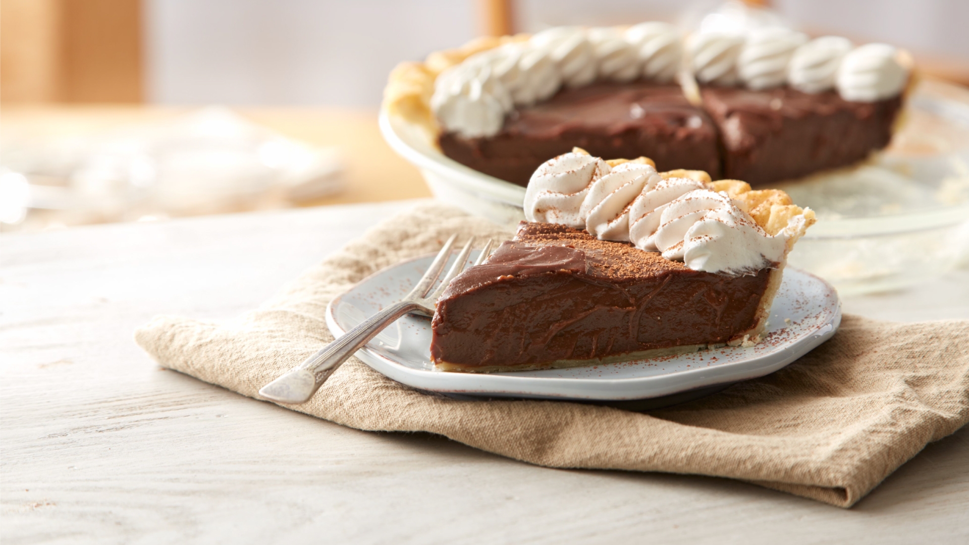 slices of chocolate cream pie topped with whipped cream and cocoa powder