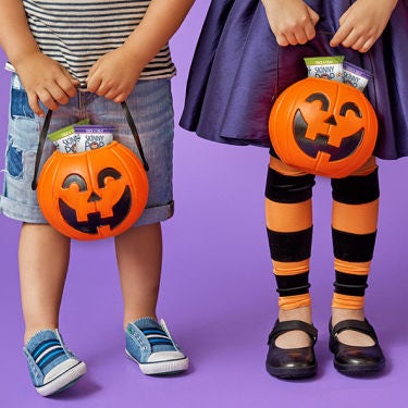 two trick or treaters holding pumpkin candy baskets