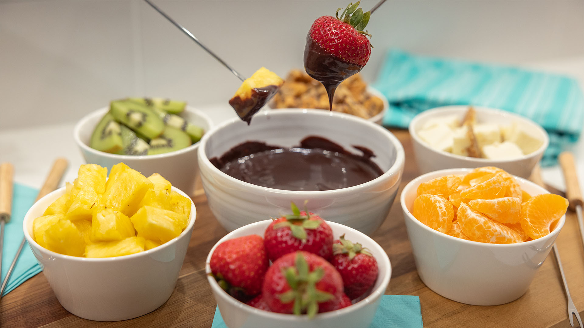 bowls of fresh fruit and cookie and cheesecake bites to dip into chocolate fondue