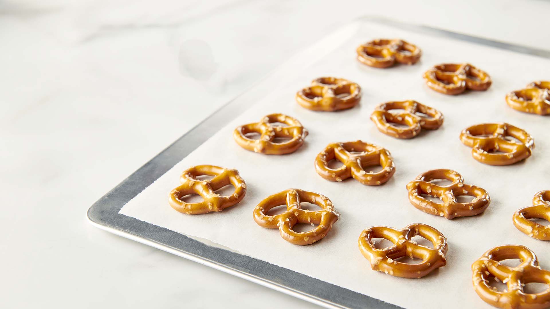 topping parchment paper with rows of small pretzels