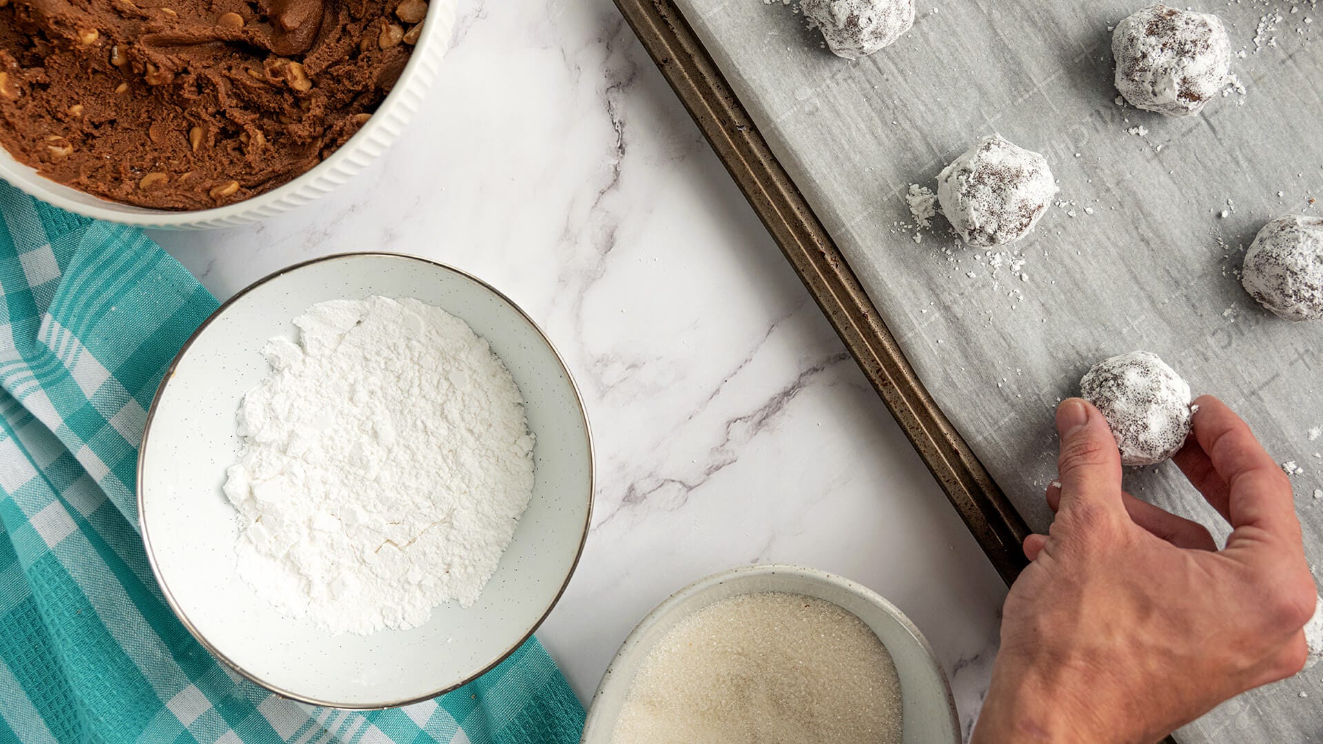 rolling cookie dough balls in powdered sugar