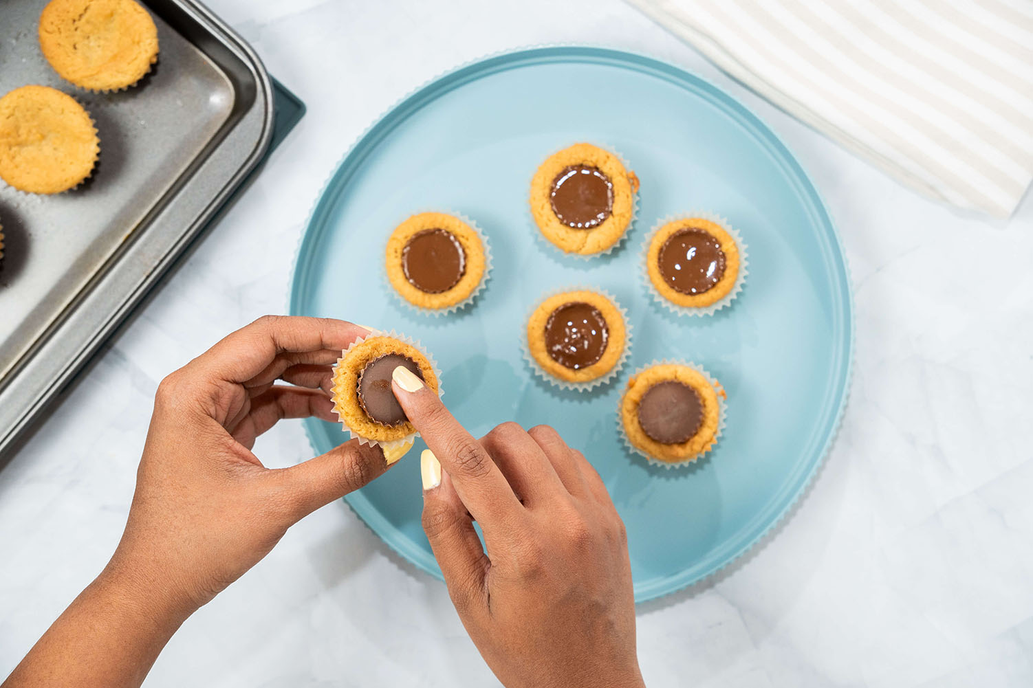 reeses cups being pressed into freshly baked cookies