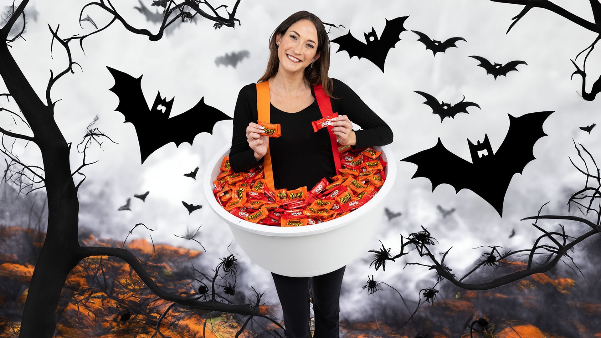 woman in trick or treat candy bowl costume filled with reeses cups and kit kat bars standing in halloween forest