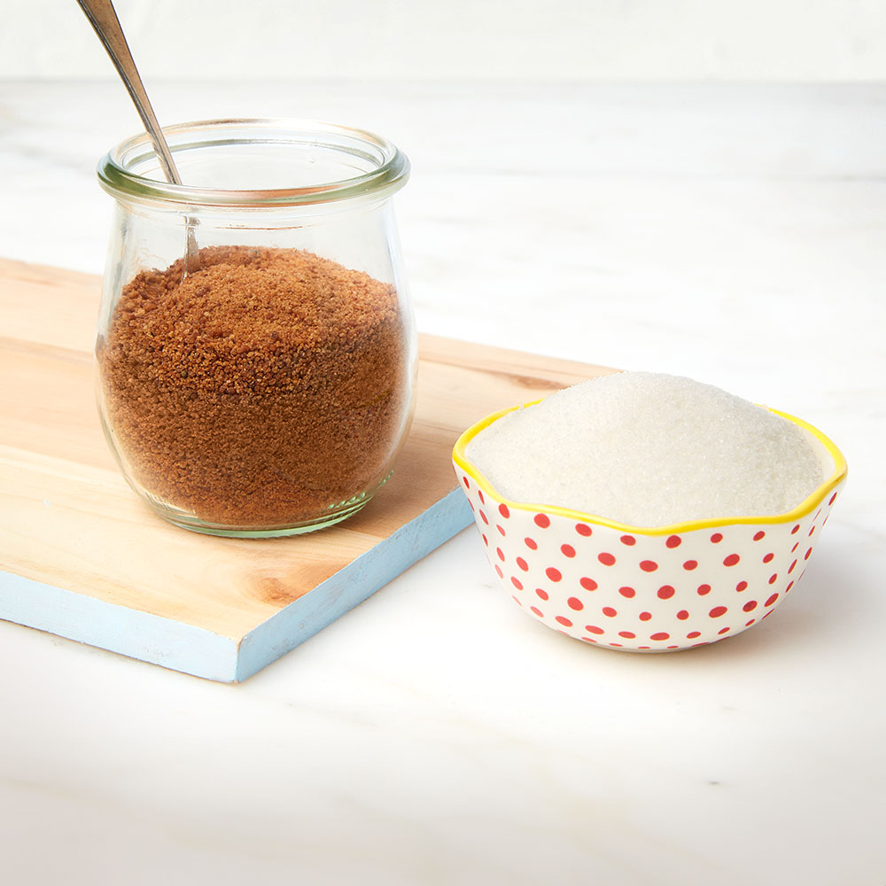 jar of brown sugar next to bowl of white sugar