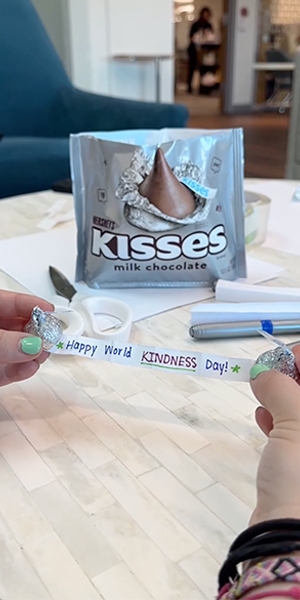 woman unraveling a world kindness day paper message attached to bottom of hersheys kisses