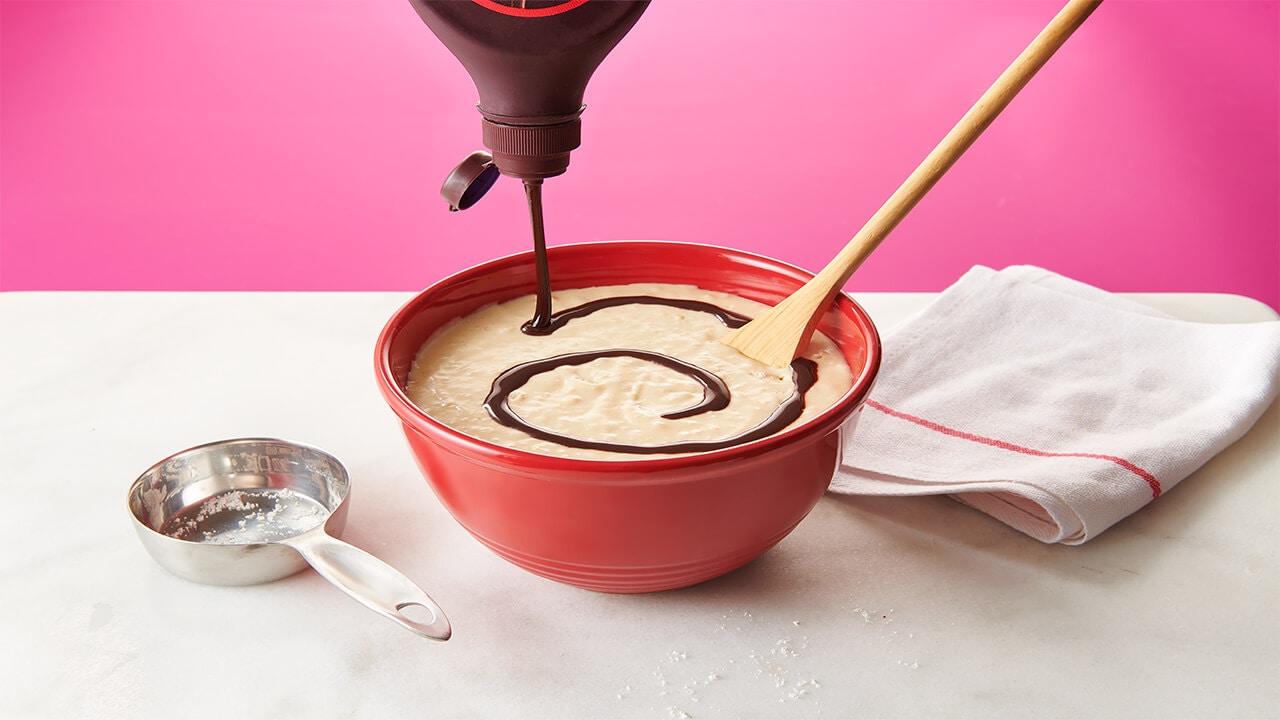 hersheys chocolate syrup being swirled into pancake mix